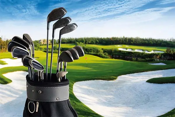 A set of the best golf clubs for 2024 is in a bag, showcased in the foreground with a lush green golf course and sand bunkers visible under a clear blue sky.