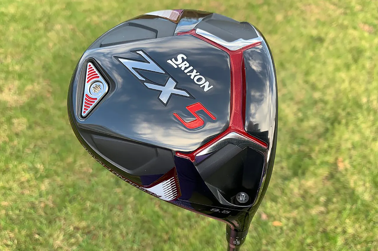 A Srixon ZX5 Driver with a sleek black, red, and silver design is showcased against the lush green grass background, making it a standout in any driver review.