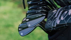 Close-up of a set of black TaylorMade P-790 golf clubs in a golf bag with a green field in the background, ready to elevate your game.