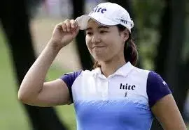 An Asian golfer in a white and blue golf shirt and cap is outdoors smiling while holding the brim of his cap One of the rising stars on the green he represents the exciting potential of golf in 